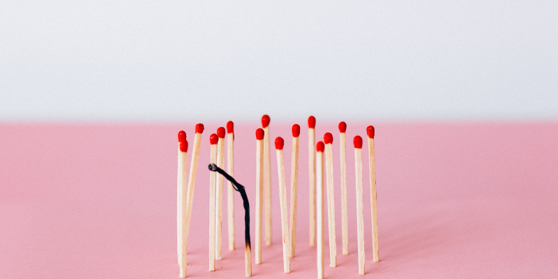 A burnt out match surrounded by unlit matches